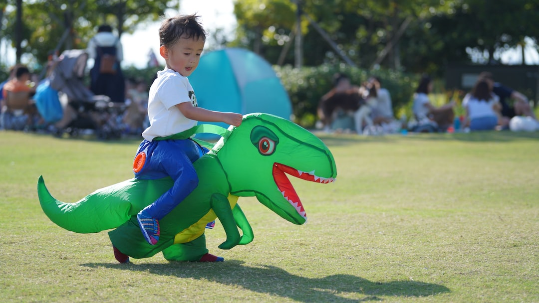 boy in white t shirt and blue denim jeans sitting on green and blue animal statue OMjyXs9VQOY jpg