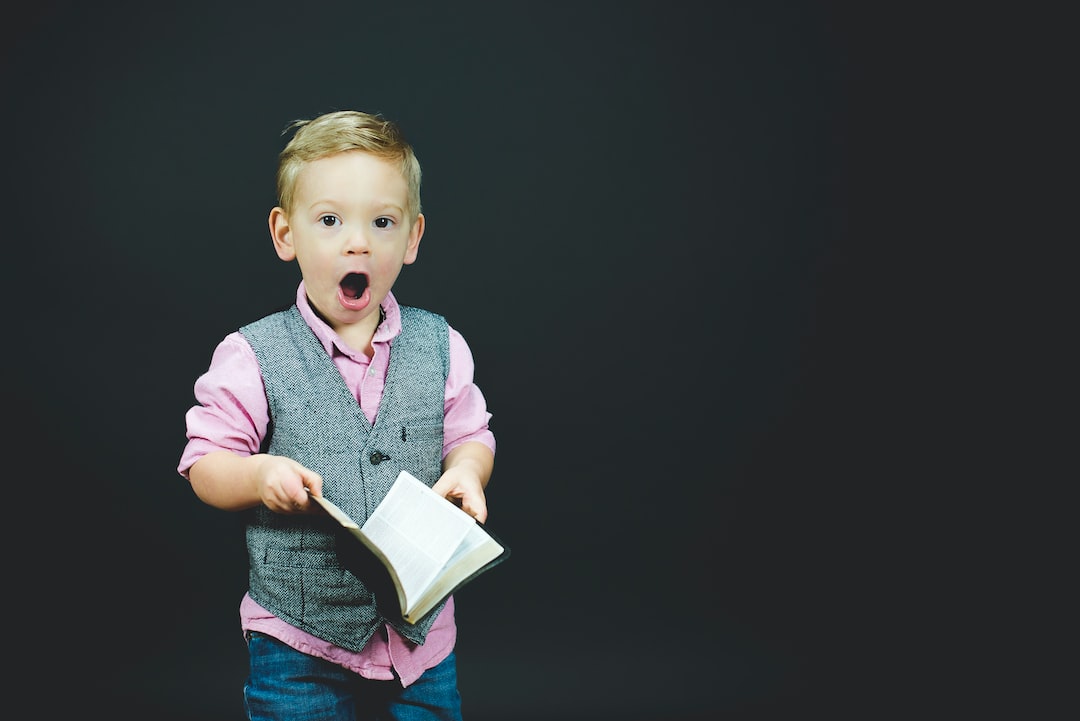 boy wearing gray vest and pink dress shirt holding book qDY9ahp0Mto jpg